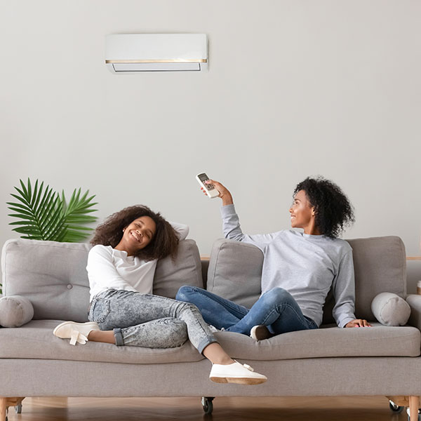 Happy african american family relaxing on sofa under air conditioner